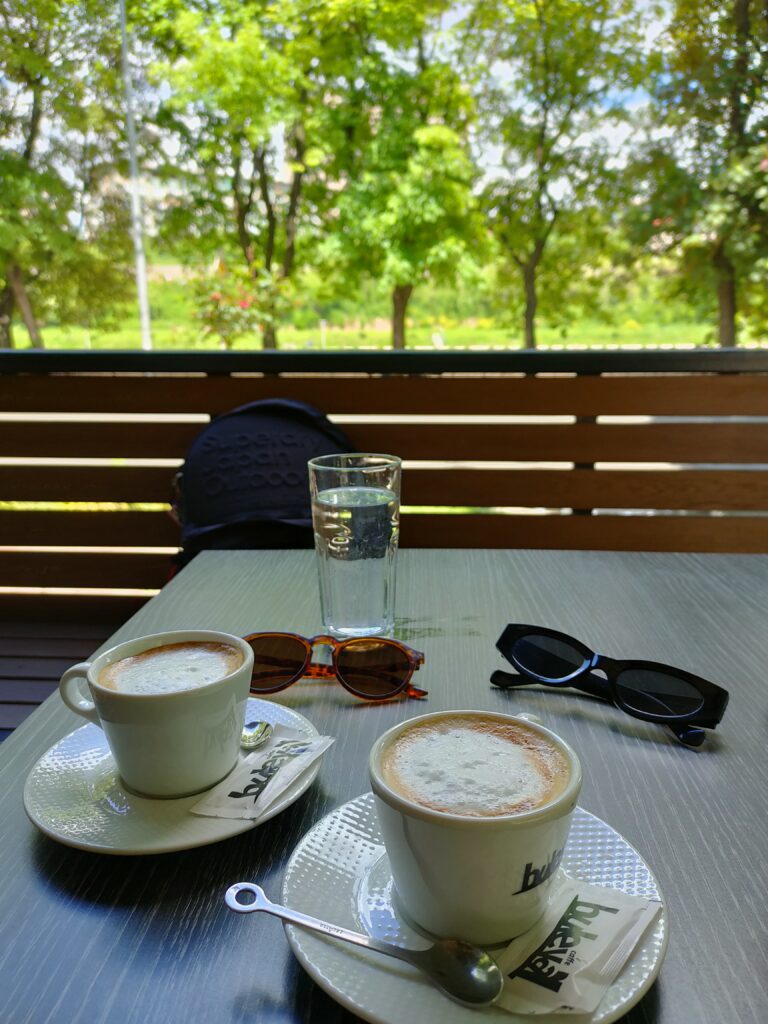 two white ceramic coffee cups with coffee and milk and a green background